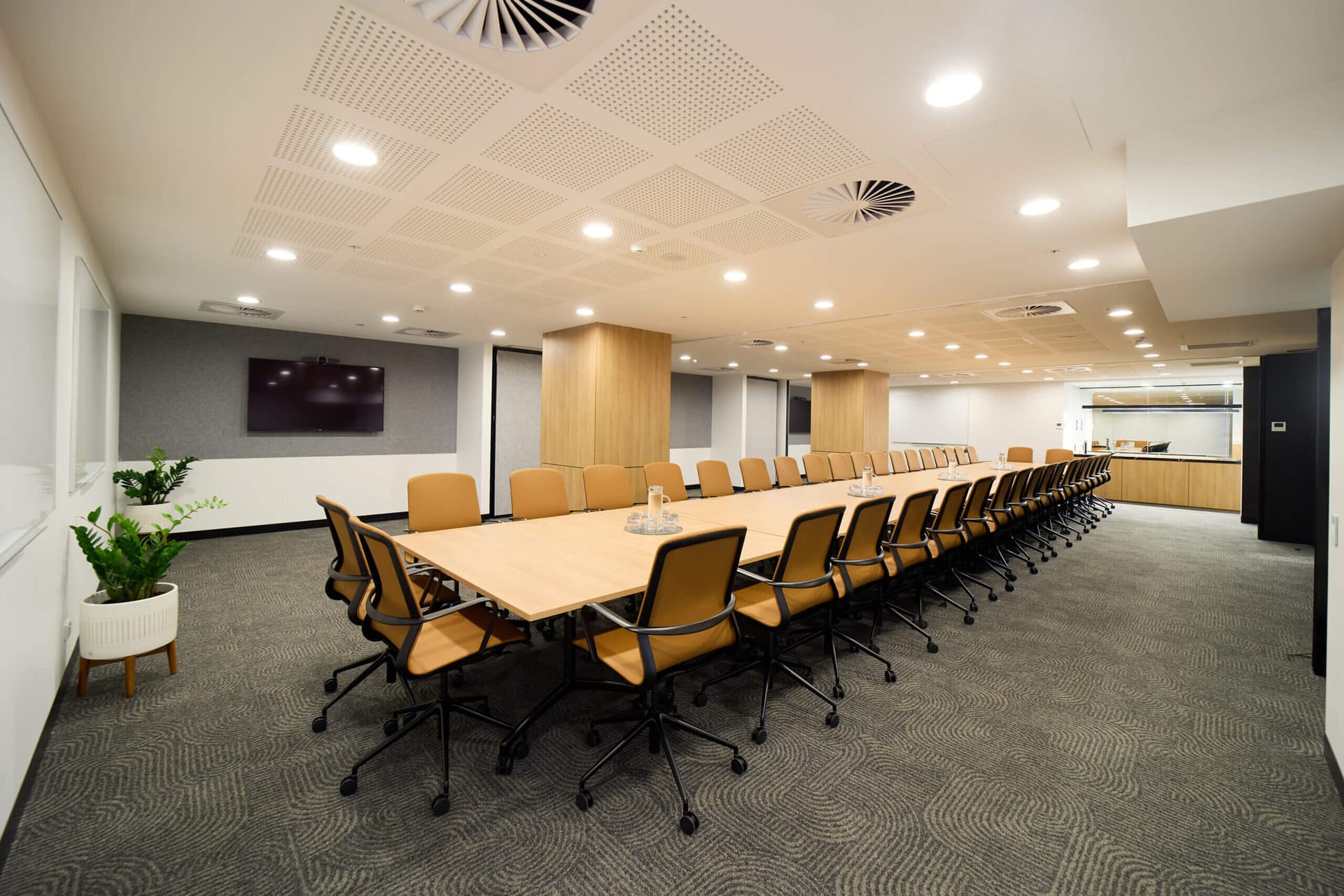 Conference room with a long table, chairs, and a TV screen, ready for a meeting.
