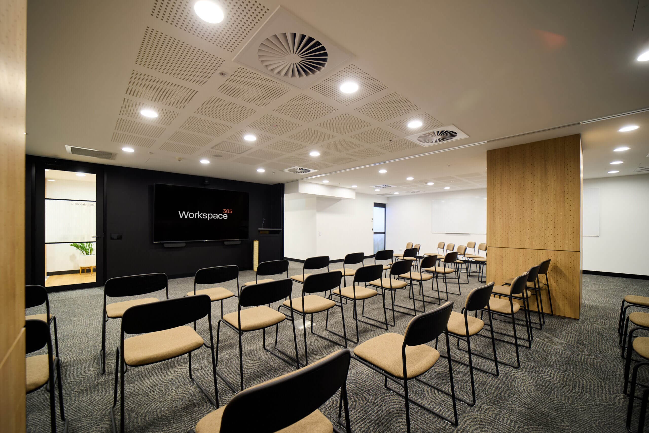 Conference room with chairs facing a screen displaying "Workspace 365".