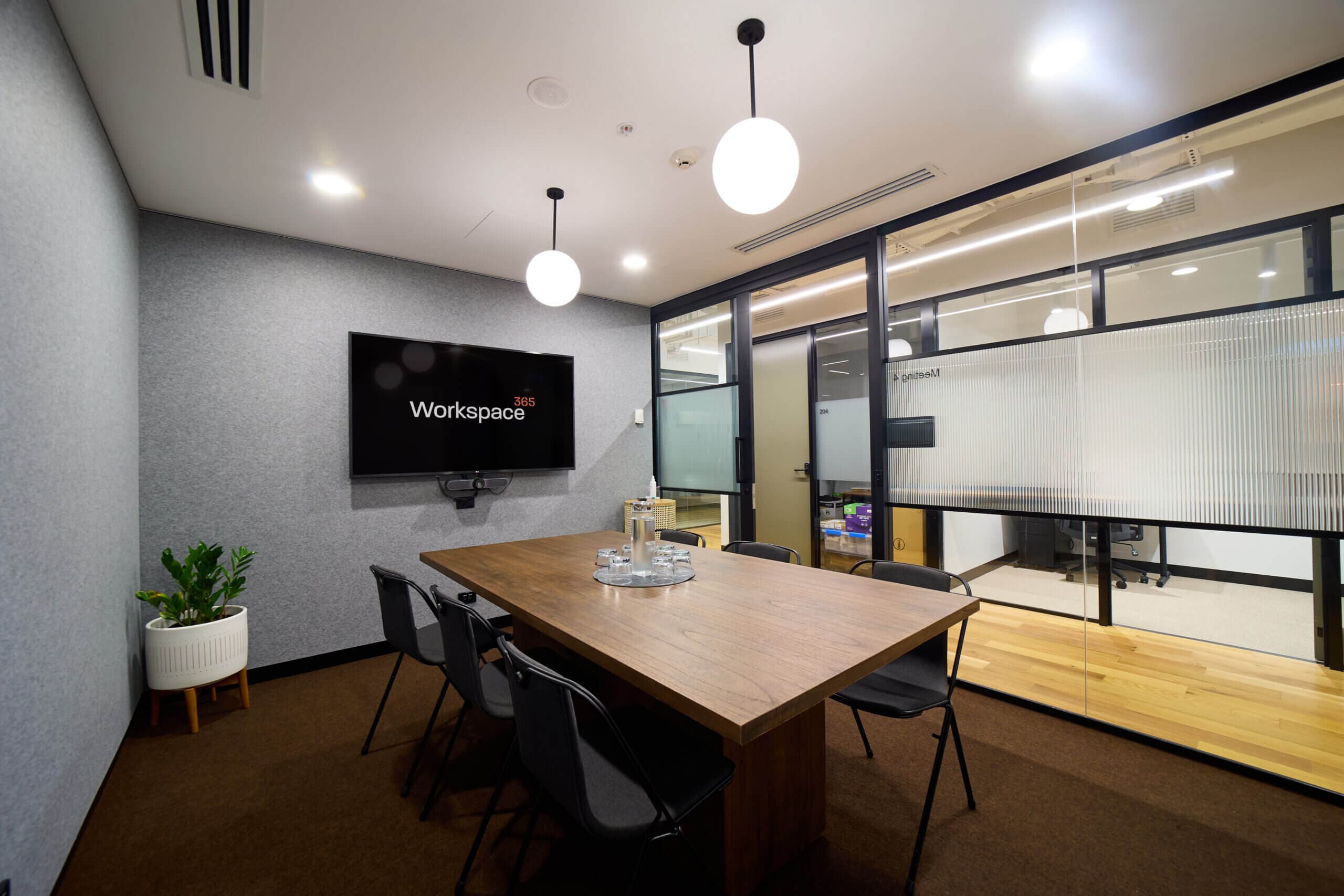 Meeting room with table, chairs, screen, and glass wall. Modern office interior.